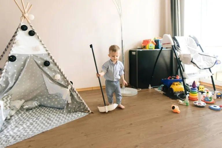 Child cleaning wooden floor in playroom with tent and toys, showcasing Royal 15/4mm Oak Barnwood flooring.