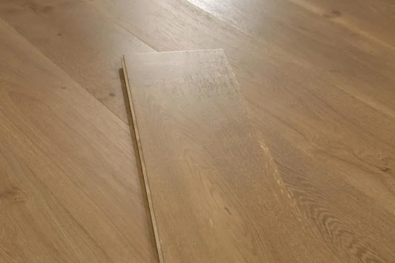 Royal 15/4mm Oak flooring in Barnwood finish, showcasing a single plank on a wooden surface, highlighting its natural grain and texture.