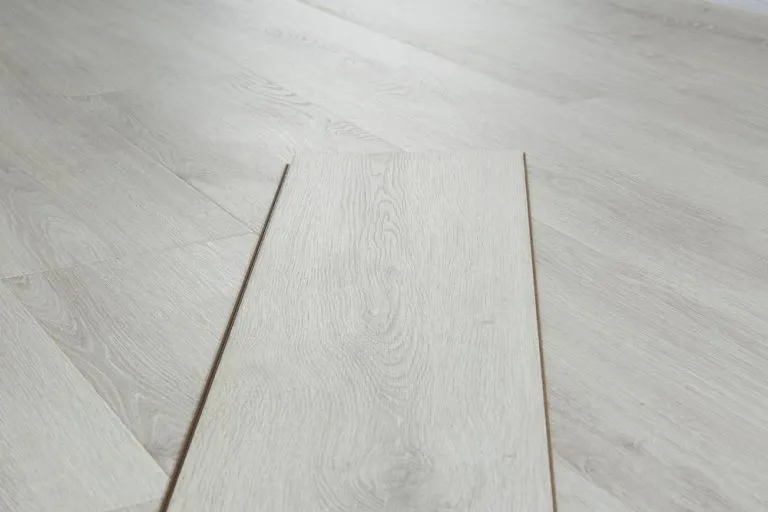 RoyalStep 12mm laminate flooring in Ashen Oak, showcasing a realistic wood grain texture and a water-resistant surface, emphasizing durability and style.