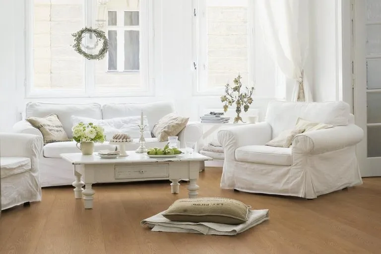 Cozy living room featuring Royal Procore Laminate flooring in Warm Oak, white furniture, decorative accents, and natural light.