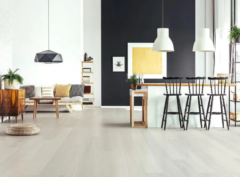 Modern interior featuring Royal 14/2mm Oak flooring in White Mist color, with stylish furniture, pendant lighting, and a black accent wall.