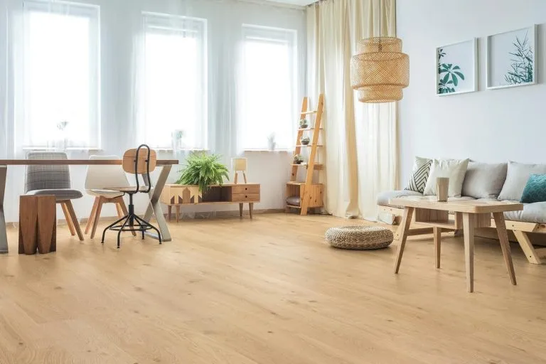 Modern living room featuring Royal 15/4mm Oak flooring in Natural color, with a dining table, stylish chairs, and decorative elements like plants and artwork.