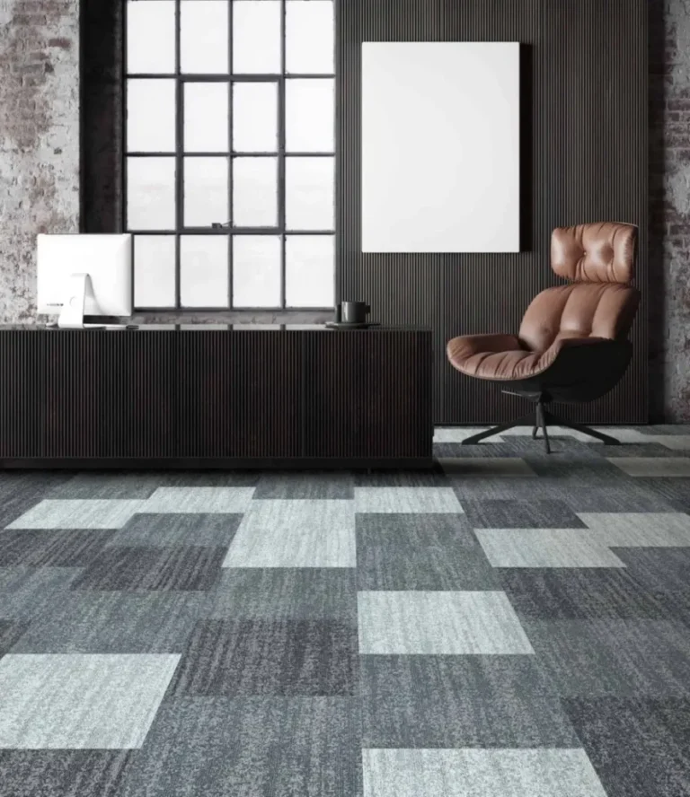 Modern office space featuring stylish carpet tiles in various shades of blue and gray, complemented by a sleek desk and comfortable chair, ideal for high-traffic commercial environments.