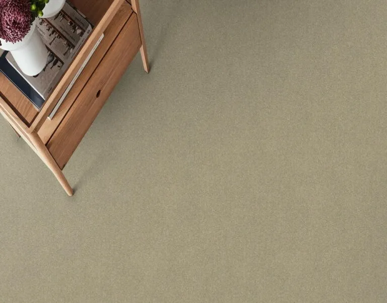 Wild River carpet in Beige Glow color, showcasing a soft Cut Pile texture, complementing a wooden furniture setting.