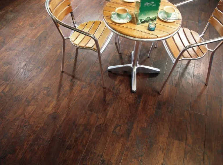 Hickory Peppercorn luxury vinyl flooring from Royal Floors, featuring a rich, dark wood appearance, complemented by a wooden table and chairs in a caf&eacute; setting.