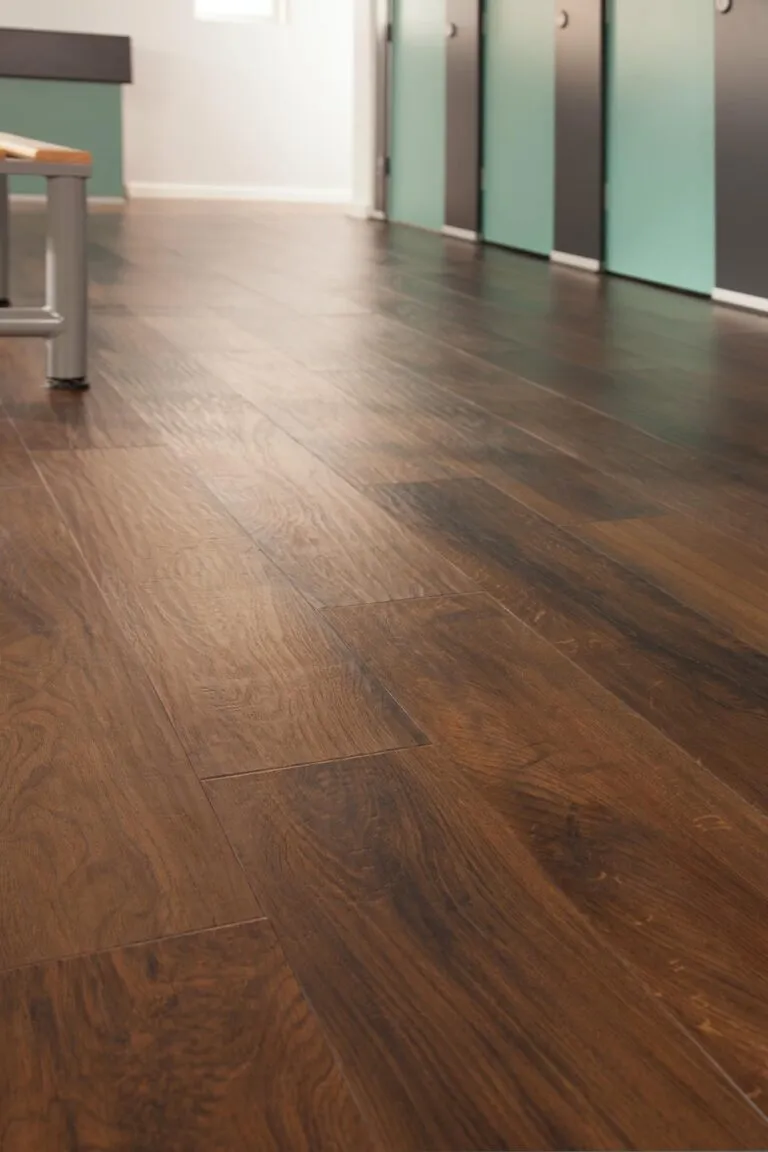 Luxury vinyl flooring in Evening Oak finish, showcasing realistic wood grain texture, ideal for high-traffic areas, with adjacent cubicle partitions in a modern setting.