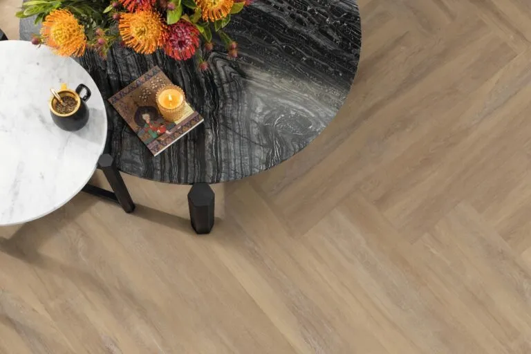 Hamden luxury vinyl flooring from Karndean, featuring a light wood design, complemented by a marble table with flowers, coffee, and a decorative book, showcasing a modern open-plan living area.
