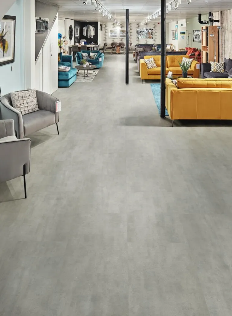 Loose Lay Originals Tiles in 'Utah' color showcased in a modern retail furniture store setting, featuring a gray stone-like floor, stylish seating arrangements, and contemporary decor elements.