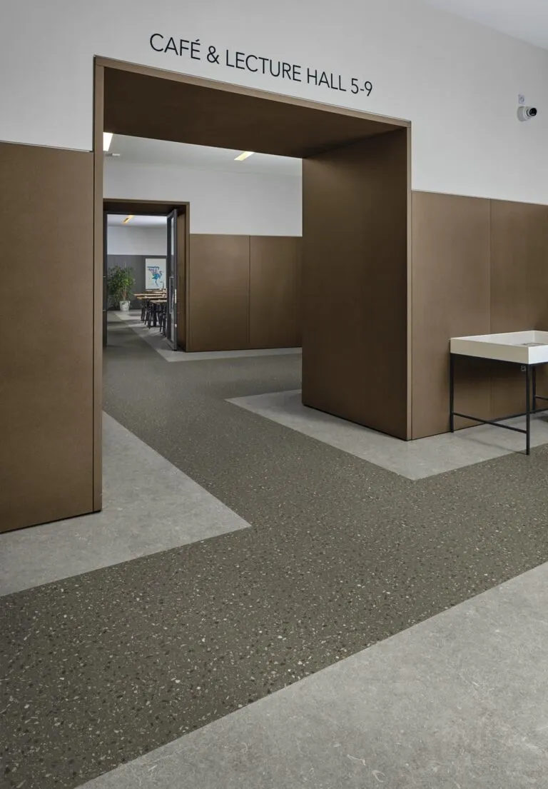Modern interior space featuring Oscuro Terrazzo flooring, brown wall panels, and a minimalist table, with signage indicating "Café & Lecture Hall 5-9."