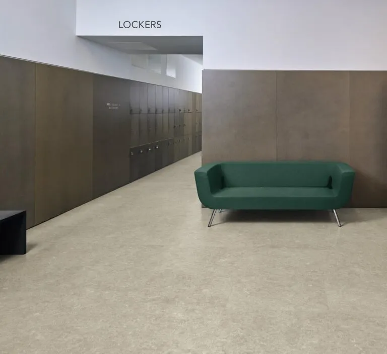 Stylish Pamplona Opus Tile flooring in light beige, featuring a modern interior with a green couch and locker area, showcasing durability and contemporary design for residential and commercial spaces.