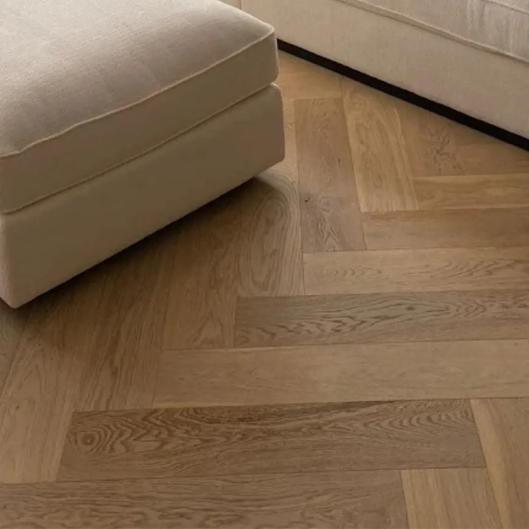 Light-colored herringbone wood flooring with a soft beige sofa