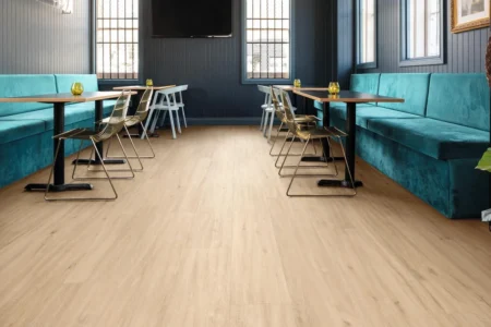 Modern restaurant interior featuring Royal Floors Loose Lay Longboard Vinyl Planks in a light wood finish, with turquoise seating, stylish tables, and a contemporary atmosphere.